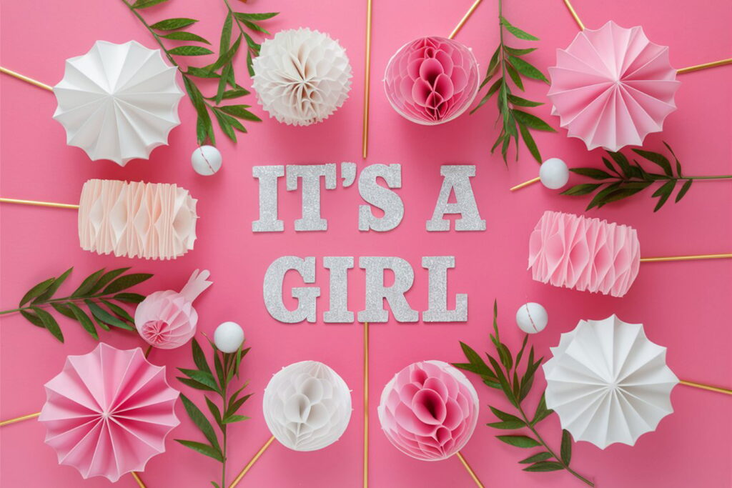 Прикраси на рожевому тлі з написом IT'S A GIRL для статті про імена для дівчаток