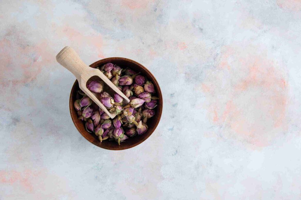 Чашка з висушеними бутонами троянди та дерев’яною лопаткою