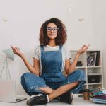 jpeg-optimizer_relaxed-young-woman-with-bronze-skin-sitting-lotus-pose-table-with-laptop-documents