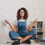 relaxed-young-woman-with-bronze-skin-sitting-lotus-pose-table-with-laptop-documents