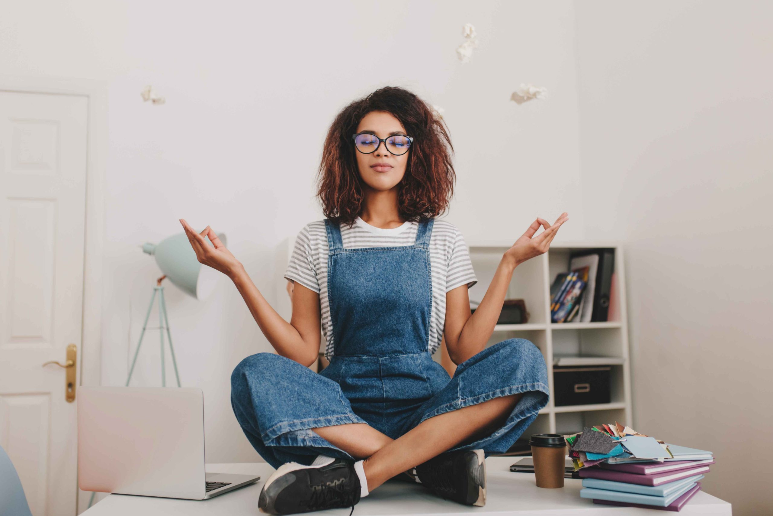 relaxed-young-woman-with-bronze-skin-sitting-lotus-pose-table-with-laptop-documents